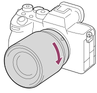 Obrázek znázorňující otáčení objektivu ve směru hodinových ručiček s fotoaparátem natočeným k sobě