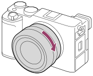 Obrázek znázorňující otáčení objektivu ve směru hodinových ručiček s fotoaparátem natočeným k sobě