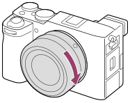 Illustrasjon som viser hvordan du dreier objektivet med klokken når kameraet er vendt mot deg