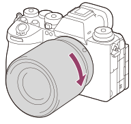 Ilustração que mostra como rodar a objetiva para a direita com a câmara virada para si