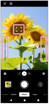 Image showing the focus frame on the upper left side, the color adjustment slider on the left side, and the brightness adjustment slider on the right side in the viewfinder of the [Photo] mode.